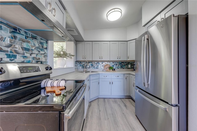 kitchen with backsplash, sink, vaulted ceiling, appliances with stainless steel finishes, and light hardwood / wood-style floors