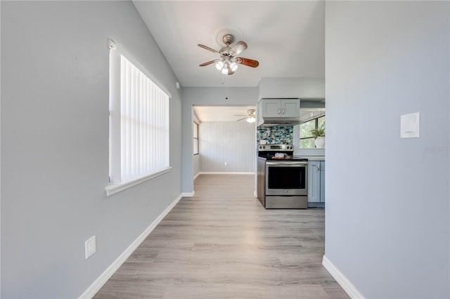 kitchen featuring backsplash, stainless steel electric stove, ceiling fan, gray cabinets, and light hardwood / wood-style floors