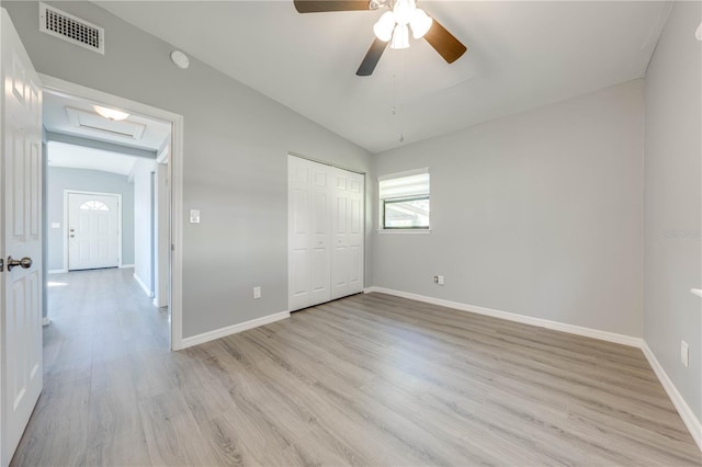 unfurnished bedroom with ceiling fan, a closet, lofted ceiling, and light hardwood / wood-style flooring