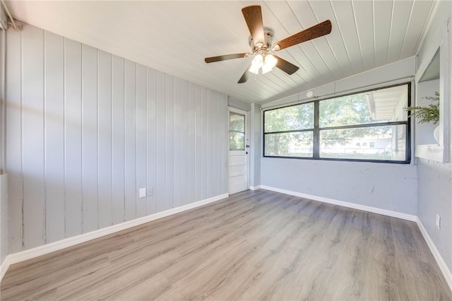 unfurnished room with wooden walls, light hardwood / wood-style flooring, ceiling fan, and lofted ceiling