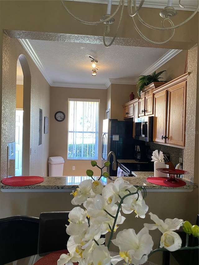 kitchen with appliances with stainless steel finishes, a textured ceiling, and crown molding