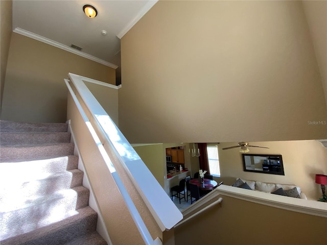 stairway featuring crown molding, carpet, and ceiling fan