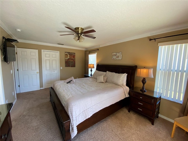 carpeted bedroom featuring ceiling fan, a closet, a textured ceiling, and ornamental molding