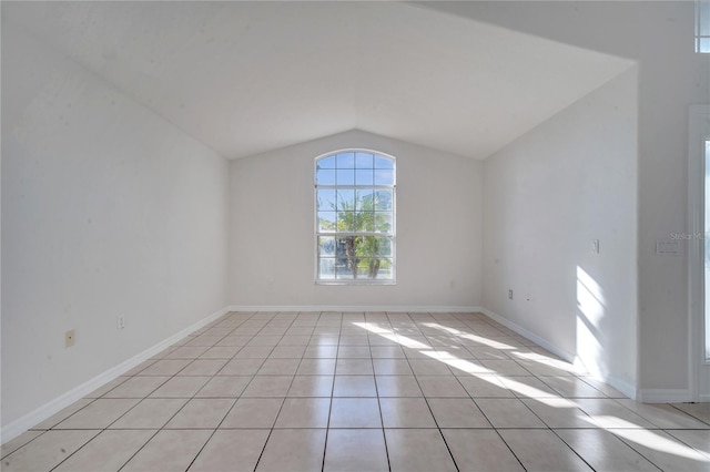 tiled spare room featuring lofted ceiling