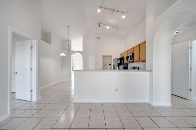 kitchen featuring hanging light fixtures, high vaulted ceiling, a chandelier, light tile patterned floors, and appliances with stainless steel finishes