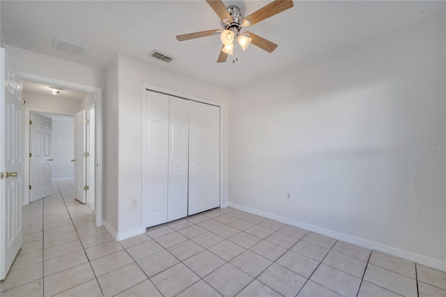 unfurnished bedroom with light tile patterned floors, a closet, and ceiling fan