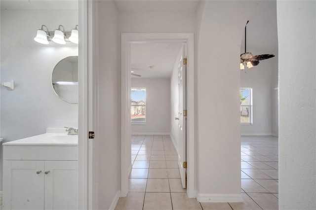 hall featuring sink, a wealth of natural light, and light tile patterned flooring