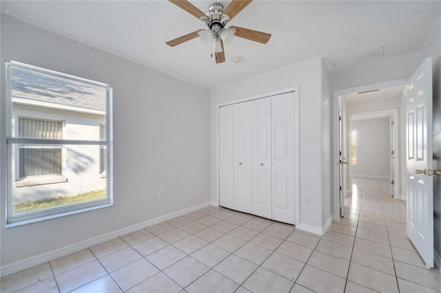 unfurnished bedroom featuring ceiling fan, a closet, and light tile patterned floors