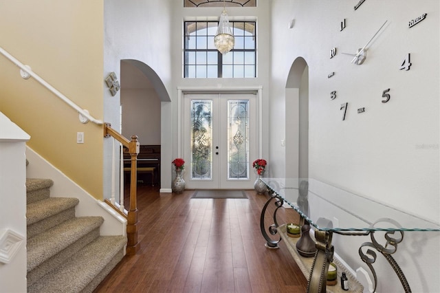 entryway featuring a chandelier, a towering ceiling, dark wood-type flooring, and french doors