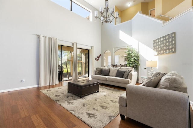 living room featuring dark wood-type flooring, a high ceiling, and a notable chandelier