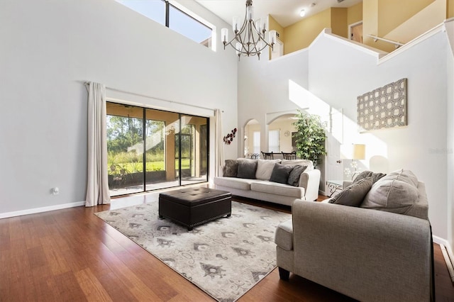 living room with a high ceiling, dark hardwood / wood-style flooring, and an inviting chandelier