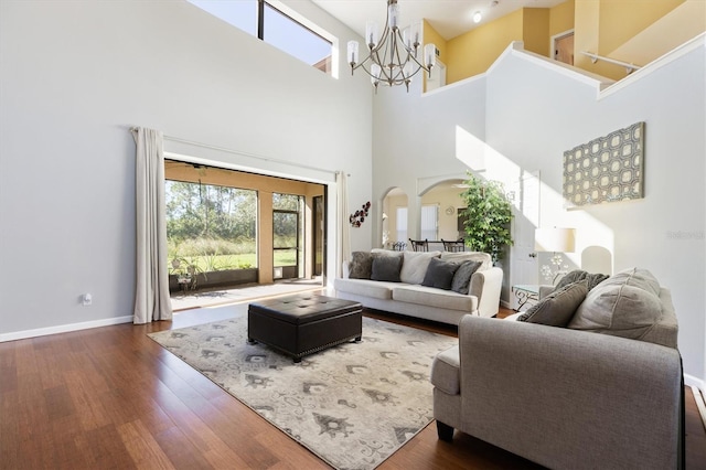 living room featuring a chandelier, a towering ceiling, and dark wood-type flooring