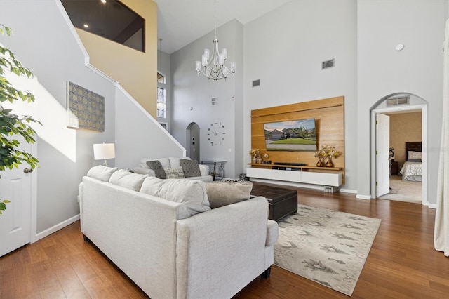 living room featuring hardwood / wood-style floors, a towering ceiling, and a notable chandelier