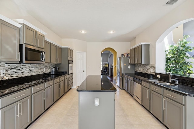 kitchen with dark stone countertops, a center island, stainless steel appliances, and sink