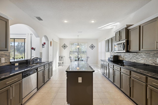 kitchen with tasteful backsplash, stainless steel appliances, a kitchen island, and a wealth of natural light