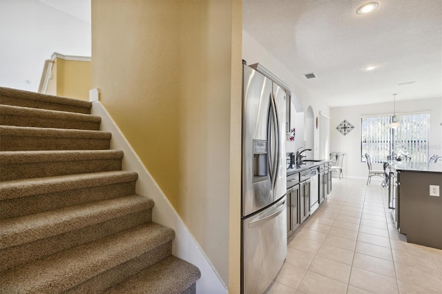 kitchen featuring pendant lighting, stainless steel fridge, light tile patterned floors, and sink