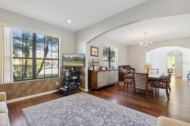 dining space with a wealth of natural light, dark hardwood / wood-style flooring, and a notable chandelier