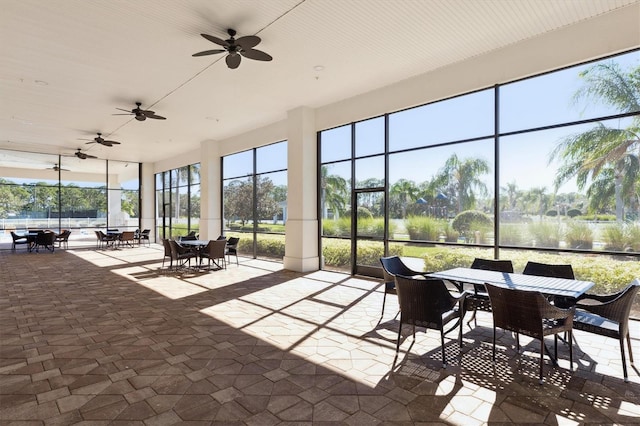 sunroom / solarium with ceiling fan, a healthy amount of sunlight, and a water view