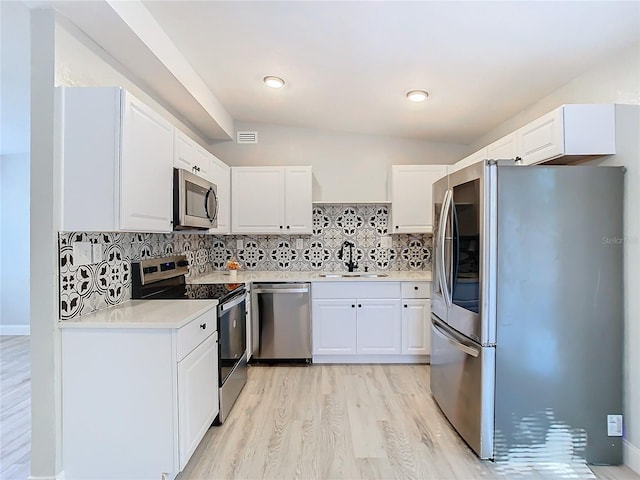 kitchen featuring white cabinets, sink, decorative backsplash, light wood-type flooring, and appliances with stainless steel finishes