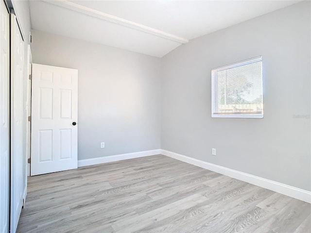 spare room featuring light hardwood / wood-style flooring and lofted ceiling