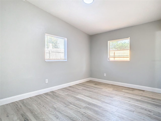 empty room with light wood-type flooring and vaulted ceiling