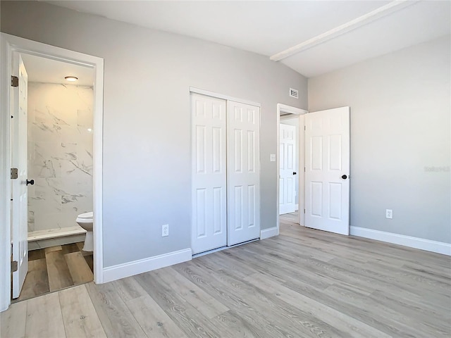 unfurnished bedroom with light hardwood / wood-style floors, connected bathroom, and a closet