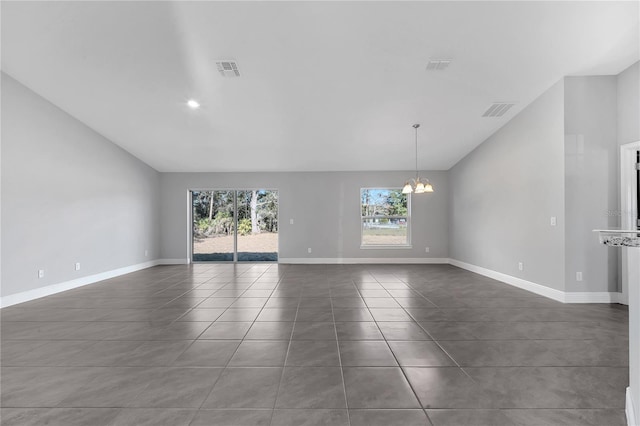 empty room with dark tile patterned floors and a chandelier