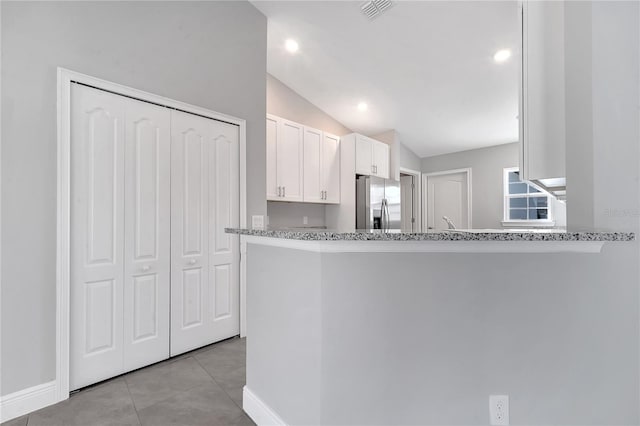 kitchen featuring kitchen peninsula, stainless steel fridge, white cabinets, and lofted ceiling