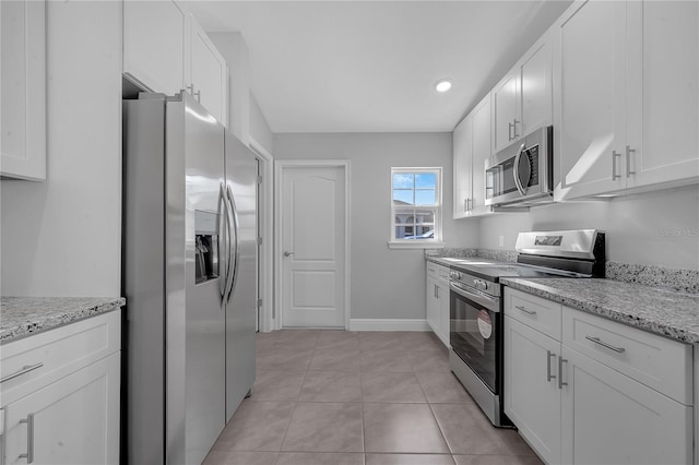 kitchen featuring light stone counters, white cabinetry, stainless steel appliances, and light tile patterned floors