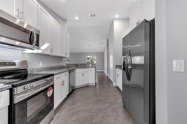 kitchen featuring white cabinetry, hanging light fixtures, stainless steel appliances, kitchen peninsula, and dark stone countertops