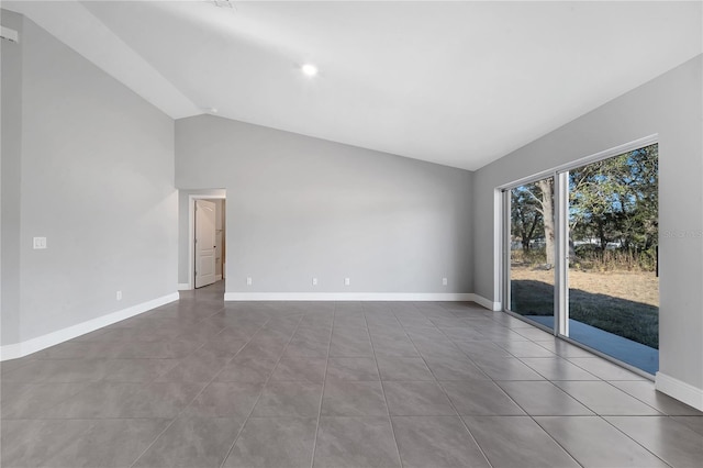 tiled empty room featuring vaulted ceiling