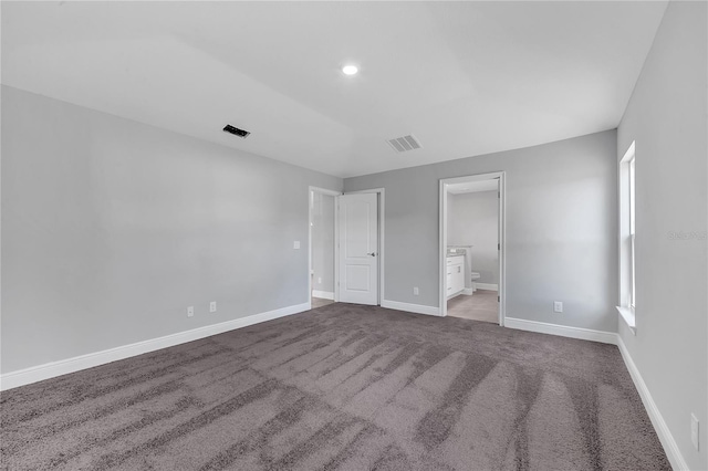 unfurnished bedroom with ensuite bathroom and carpet floors