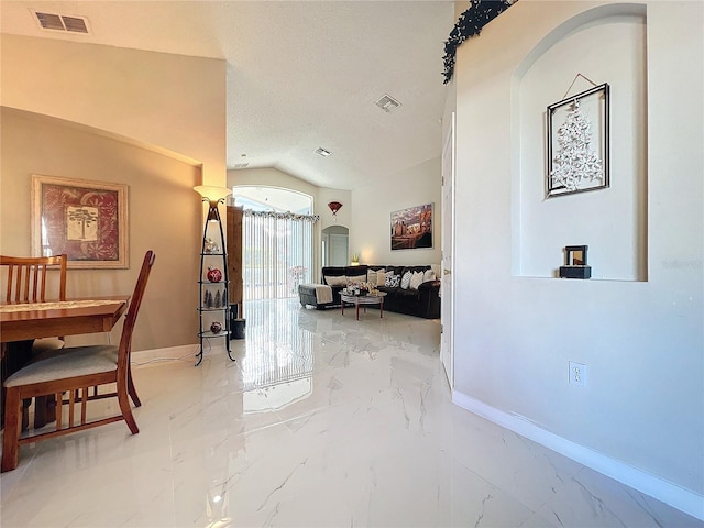 hallway with a textured ceiling and vaulted ceiling