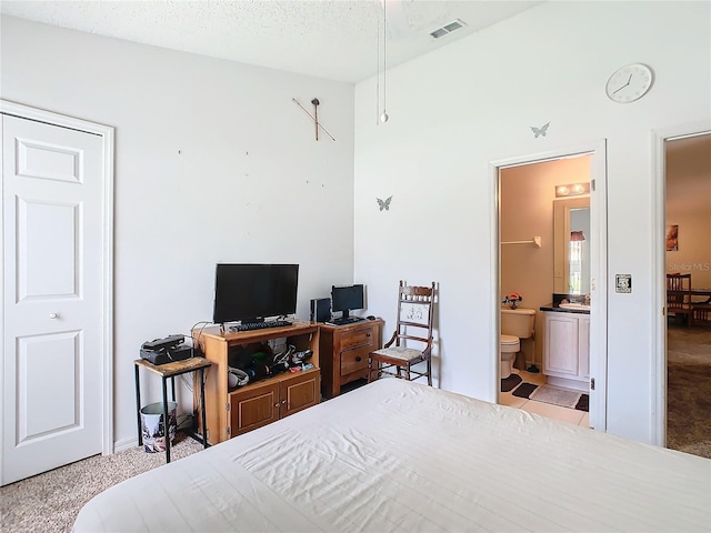 carpeted bedroom featuring a textured ceiling and connected bathroom