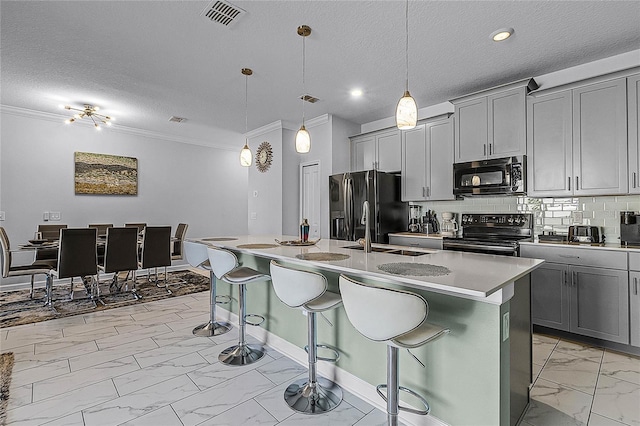 kitchen featuring decorative light fixtures, stainless steel appliances, a breakfast bar area, and an island with sink