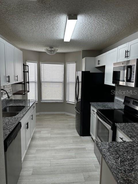 kitchen featuring dark stone countertops, white cabinetry, and appliances with stainless steel finishes