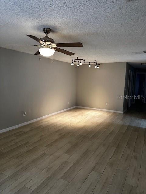 unfurnished room featuring hardwood / wood-style flooring, ceiling fan, and a textured ceiling