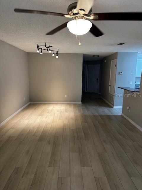 spare room featuring ceiling fan, wood-type flooring, and a textured ceiling