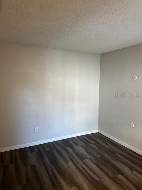 empty room featuring dark hardwood / wood-style floors and a textured ceiling