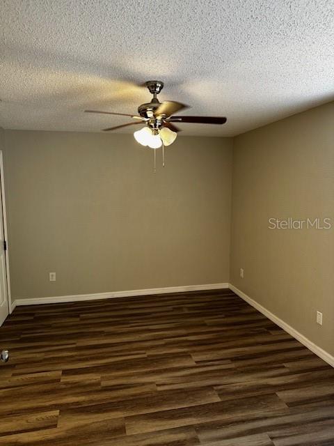 empty room featuring dark hardwood / wood-style floors, ceiling fan, and a textured ceiling