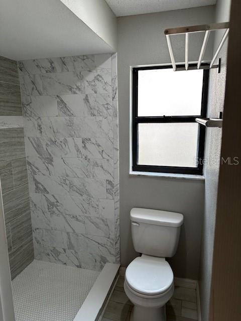 bathroom featuring toilet and tiled shower