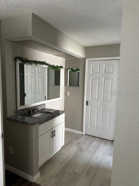 bathroom with hardwood / wood-style floors, vanity, and a textured ceiling