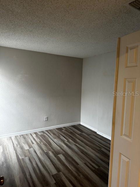 unfurnished room with a textured ceiling and dark wood-type flooring