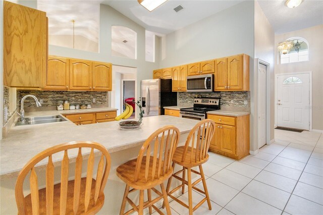 kitchen with sink, a breakfast bar area, light tile patterned floors, kitchen peninsula, and stainless steel appliances