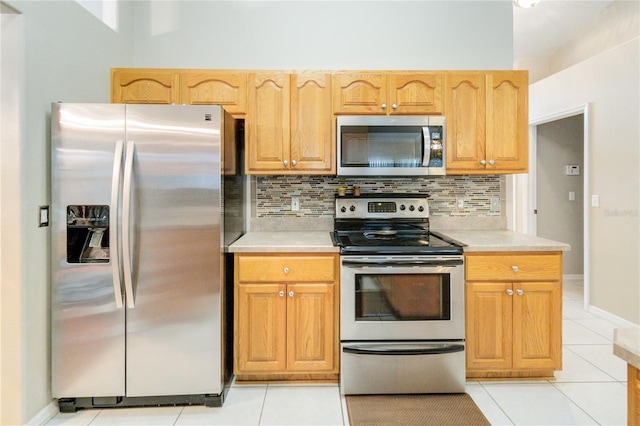 kitchen with appliances with stainless steel finishes, light tile patterned floors, and backsplash