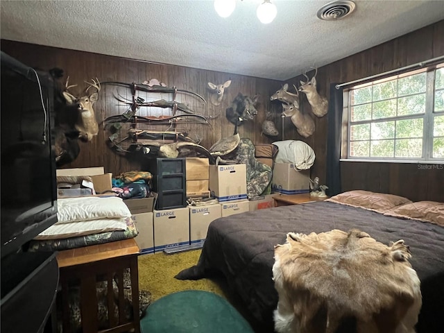 carpeted bedroom with a textured ceiling and wood walls