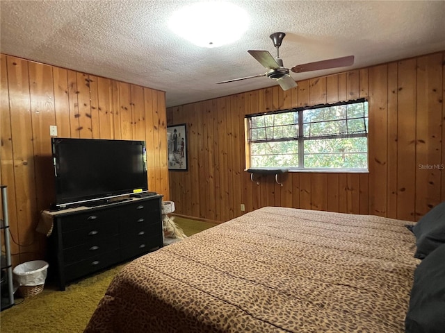 carpeted bedroom featuring wood walls, ceiling fan, and a textured ceiling