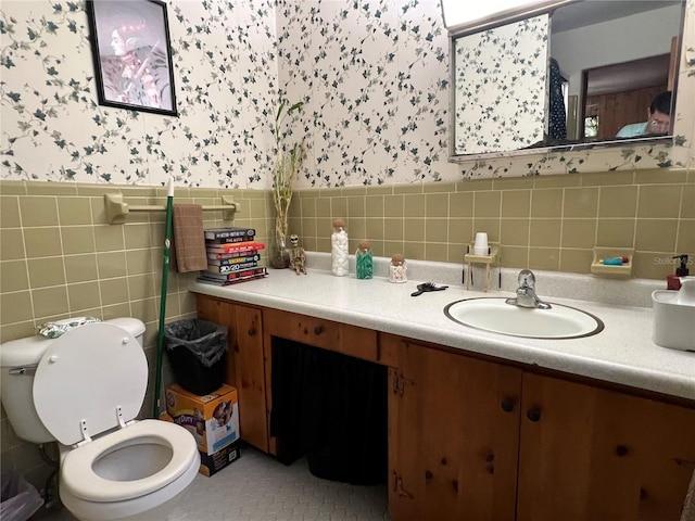 bathroom with tile patterned flooring, vanity, toilet, and tile walls