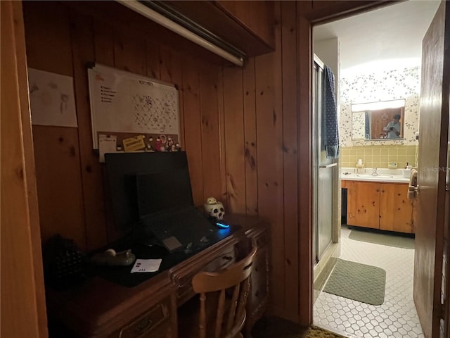 office space with wood walls, light tile patterned floors, and sink