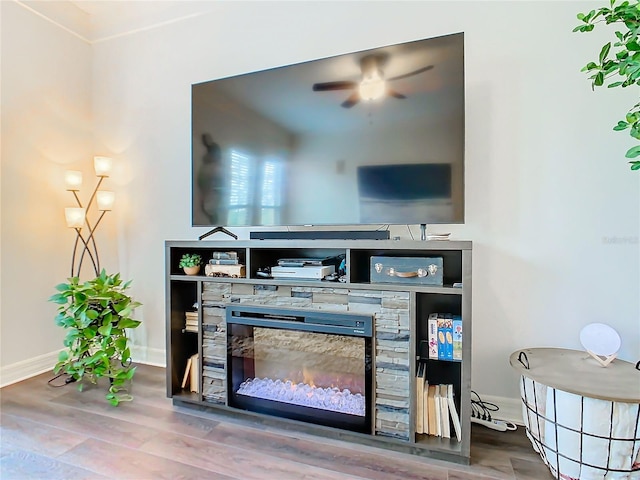 room details with hardwood / wood-style flooring, ceiling fan, and a stone fireplace